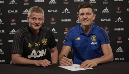 Harry Maguire firma su contrato acompañado del entrenador del United, Ole Gunnar Solskjaer.