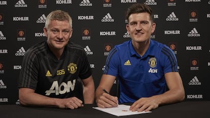 Harry Maguire firma su contrato acompañado del entrenador del United, Ole Gunnar Solskjaer.