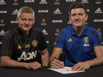 Harry Maguire firma su contrato acompañado del entrenador del United, Ole Gunnar Solskjaer.