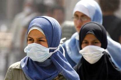 Mujeres libanesas caminan cubiertas con mascarillas ante el polvo que se respira en Beirut tras los bombardeos.