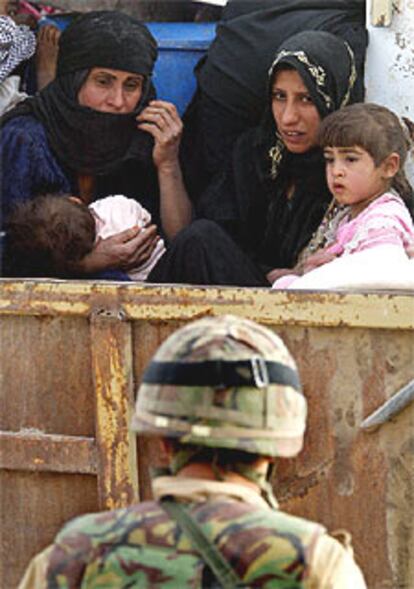 Una familia de refugiados que huye de Basora observa a un soldado británico en un control militar.