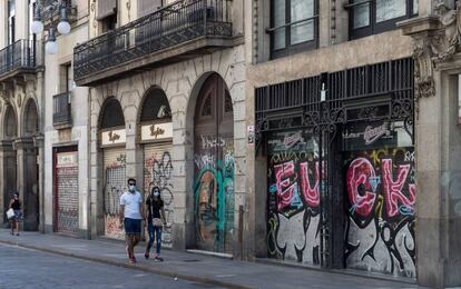 Una parella passeja entre comerços tancats al carrer Ferran de Barcelona.