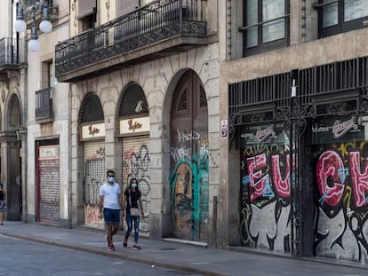 Una parella passeja entre comerços tancats al carrer Ferran de Barcelona. 