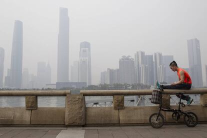 Un joven descansa a la orilla del río Perla cerca de un nuevo complejo de edificios comerciales y residenciales en Cantón, China.