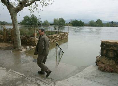 Un vecino circula por una calle a punto de inundarse a causa de la crecida del Ebro en la localidad tarraconense de Miravet, donde el río ha alcanzado un caudal de 1.880 metros cúbicos por segundo.