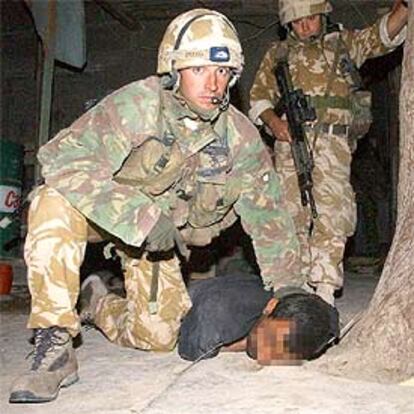 Un soldado británico sujeta a un prisionero iraquí, capturado durante un registro nocturno en Um Qasr.