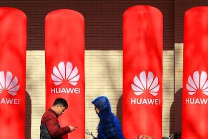 People walk past logos of Huawei in Huaian