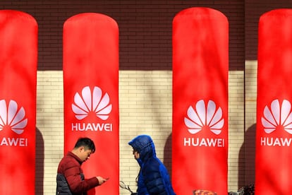 People walk past logos of Huawei in Huaian