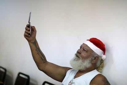 Un estudiante con gorro de Papá Noel se fotografía con su teléfono móvil.