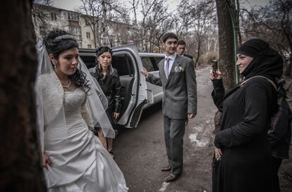 Una joven novia sale de la limusina que han alquilado para su boda, en un suburbio a las afueras de Bishkek, mientras su prima le toma una foto con el móvil.