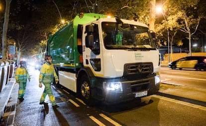 Dos trabajadores de recogida de residuos junto a uno de los nuevos camiones eléctricos adquiridos por el Ayuntamiento de Barcelona.