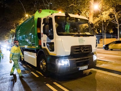 Dos trabajadores de recogida de residuos junto a uno de los nuevos camiones eléctricos adquiridos por el Ayuntamiento de Barcelona.