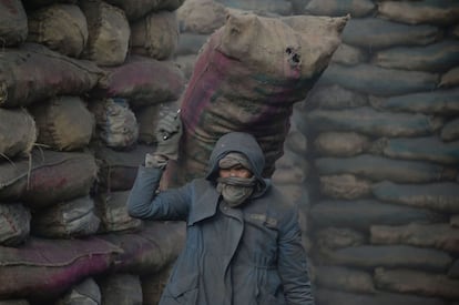 Un trabajador afgano descarga un saco de carbón de un camión en una mina en Kabul (Afganistán).