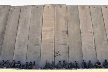 Soldados israelíes descansan a la sombra del muro que separa a Israel de la franja de Gaza.