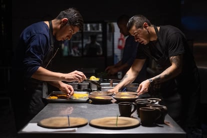 Arturo y Bayron, miembros del equipo del restaurante oaxaqueño Alsonsina, sirven platillos en la cocina del proyecto culinario familiar.