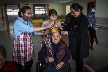 Voluntarios colocan una corona de papel a una anciana en la celebración del Centro de Bienestar de Hangzhou.