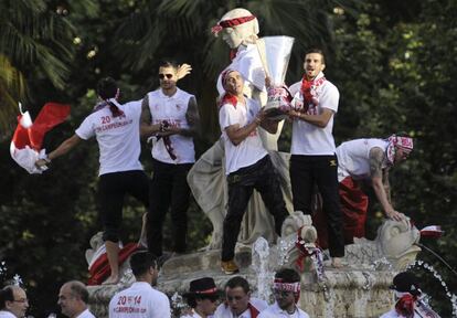 Los jugadores del Sevilla, subidos a la estatua de Hispalis, en la Puerta de Jerez.