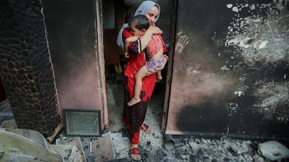 Souhila Belkati y su hijo en lo que queda de su casa tras el paso del fuego en Bejaia (Argelia).
