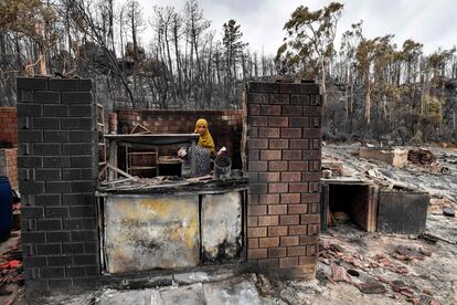 Una mujer busca objetos entre los escombros de un restaurante calcinado tras los incendios en la ciudad de Melloula (Argelia), este miércoles. 