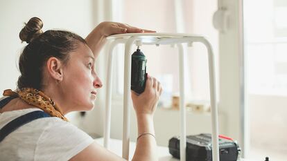 Una mujer usando e atornillador eléctrico