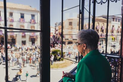 Una mujer observa la procesión de Semana Santa desde una terraza.