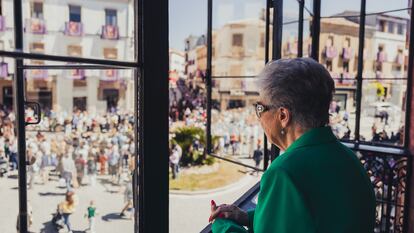 Una mujer observa la procesión de Semana Santa desde una terraza.