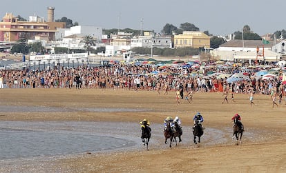 Los caballos toman la playa gaditana mientras un ejército de bañistas protegidos por sombrillas siguen la carrera.