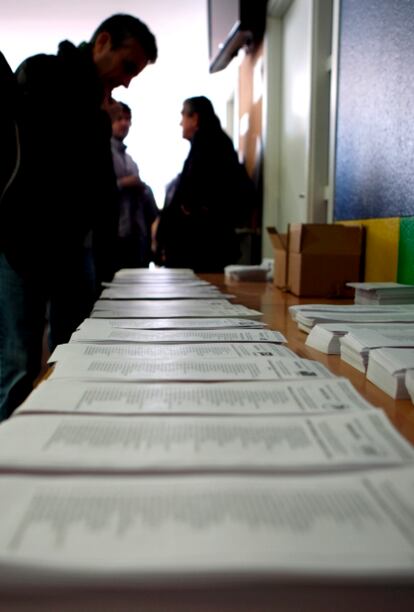 Varias personas buscan las papeletas de los candidatos antes de emitir su voto en un colegio electoral del barrio barcelonés del Poble Nou