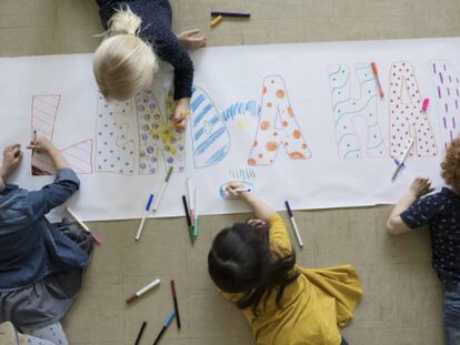 Cuatro niños pintan un cartel.