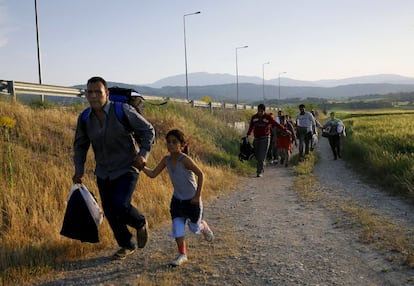 Sahin Serko, un ciudadano sirio kurdo, coge de la mano a su hija Ariana, de siete años, para escapar de las patrullas de la policía griega antes de cruzar la frontera con Macedonia, junto a otros 45 sirios.