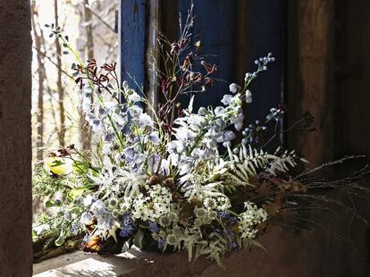 Isabel Marías se inspira en la ventana de madera del cuadro 'Around the Corner' para montar una composición de flores de los géneros Delphinium, Leucadendron y Ornithogalum (imagen de arriba). Los rayos del sol destacan los colores del ramo, de tonalidades blanca, burdeos y violeta.