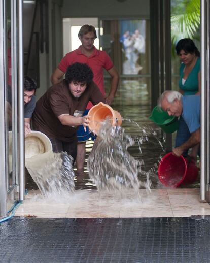 Unas personas tratan de sacar el agua de un edificio en el barrio de Belgrano, Buenos Aires el 2 de abril de 2013, después de las intensas lluvias caídas en la capital argentina.