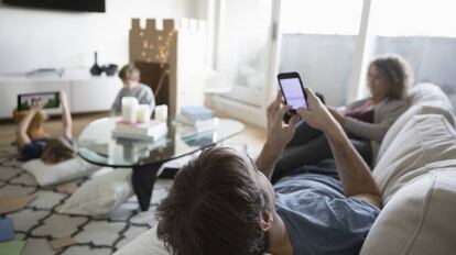 Una familia reunida en el salón mientras usa dispositivos electrónicos.