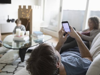 Una familia reunida en el salón mientras usa dispositivos electrónicos.