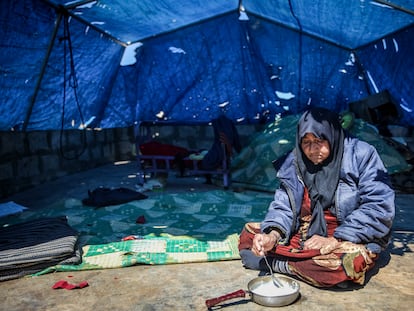 Una mujer come en la entrada de la tienda de campaña en la que vive en Idlib (Siria), en vísperas del mes sagrado del Ramadán.