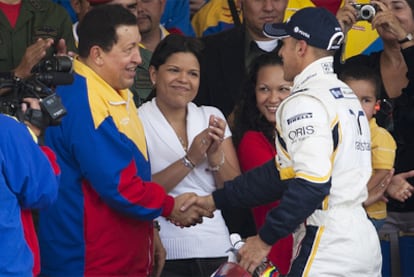El presidente de Venezuela, Hugo Chávez, saluda al piloto Pastor Maldonado.