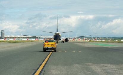 A vehicle guides an aircraft on a runway at Madrid-Barajas airport.