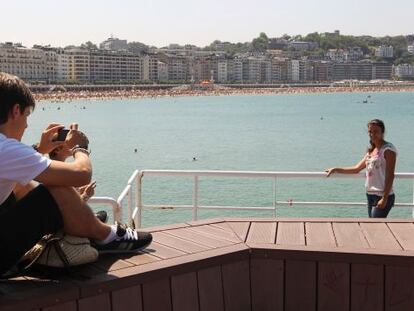 Una pareja de turistas se fotografía en la playa de La Concha de San Sebastián. 