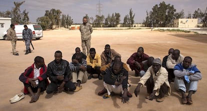Un grupo de inmigrantes es custodiado junto a un centro de internamiento para extranjeros en Misrata.