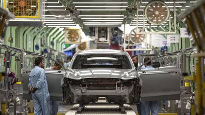 Varios trabajadores de la planta de pintura de Ford en Almussafes (Valencia), revisan una carrocería tras su paso por la zona de pintura.