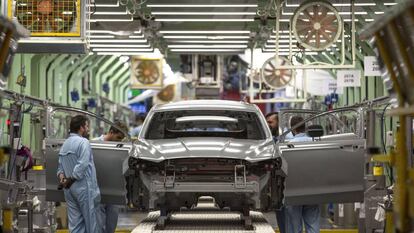 Varios trabajadores de la planta de pintura de Ford en Almussafes (Valencia), revisan una carrocería tras su paso por la zona de pintura. 