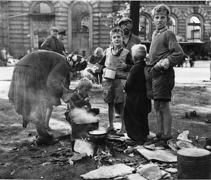 Una madre alemana cocina para su familia en una calle del Berlín de 1945