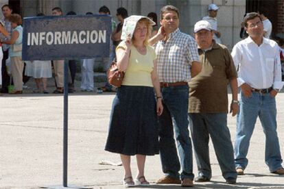 Un grupo de personas tratan de resguardarse del calor mientras esperan en una cola.