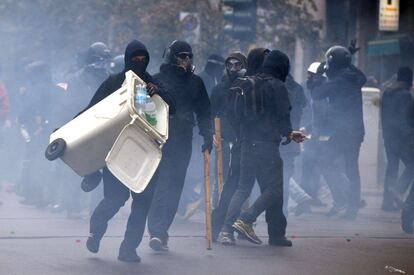 Decenas de antisistema, con el rostro cubierto y vestidos de negro, se arman con palos y cubos de basura para mostrar su rechazo a la Exposición Universal.