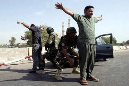 Soldados iraquíes registran a dos civiles, ayer en un puesto de control de Bagdad.