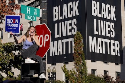 Una mujer grita el triunfo de Biden en una de las principales avenidas de Washington DC frente a un cartel del movimiento que denuncia la brutalidad policial contra los afroamericanos.