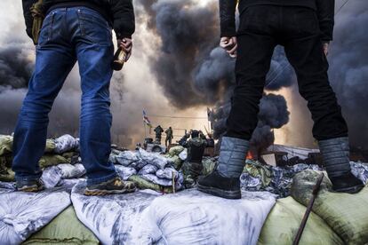 Un par de manifestantes antigubernamentales se suben a lo alto de las barricadas durante los enfrentamientos que mantuvieron con la policía antidisturbios en Kiev.