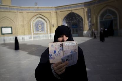 Una mujer muestra su cuaderno de votaciones después de haber votado en Qom.