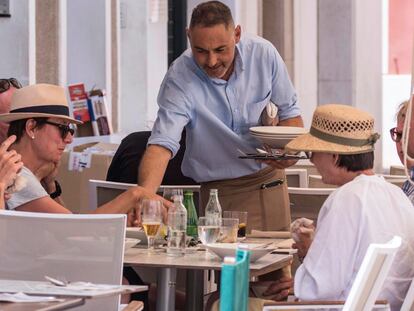 Un camarero sirve bebidas en una terraza en Mahón (Menorca).