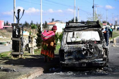 Una mujer mira un coche quemado tras los enfrentamientos en El Alto (Bolivia).